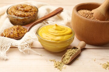 Different types of mustard on wooden table, closeup