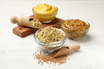 Different types of mustard on white marble table, closeup