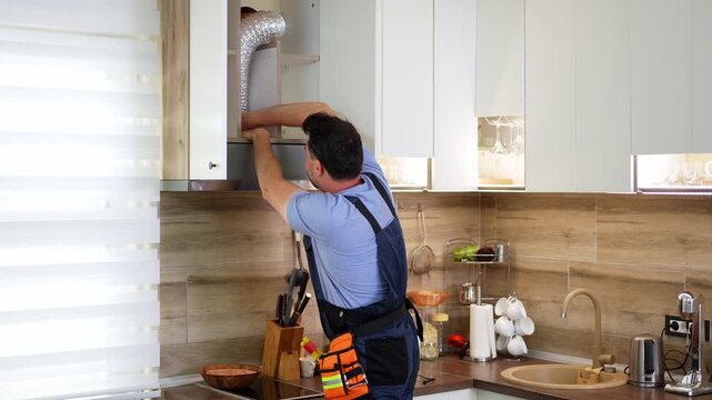Handyman installing extractor hood in kitchen