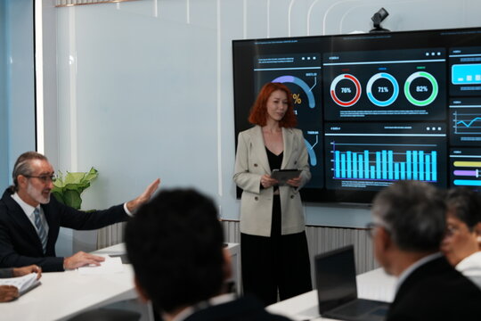Female employee in suit presents chart data, sales report to shareholder meeting to decide on planning and working strategy in conference room.