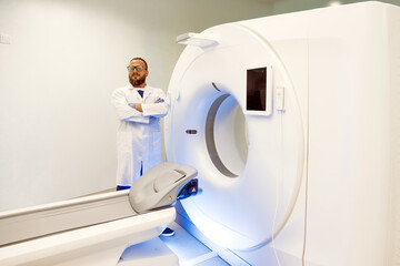 Medical professional in white coat stands confidently beside advanced computer tomography machine,...