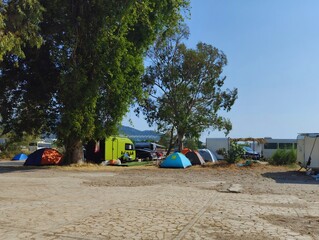 Image of camping caravans and tents on a sandy grassy campground on a beach sea coastline with blue sky photography hd quality wallpaper perfect for campaigns sunny summer day 