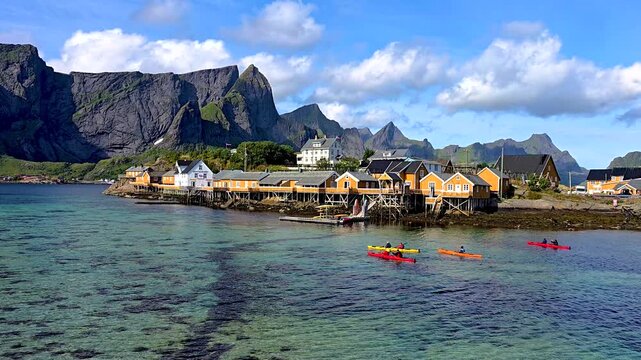 Experience the breathtaking beauty of Lofoten, Norway, where vibrant kayaks glide across crystal-clear waters, surrounded by towering mountains under a clear blue sky.