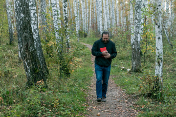 A bearded man walks through the forest