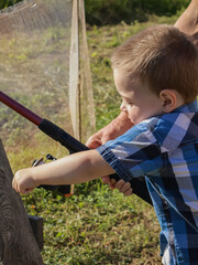 With his father's help, the boy turns the spinning reel.