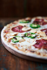 Pizza with salami, mozzarella cheese and jalapeno pepper. Wooden background. Soft focus. Copy space.	