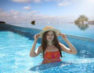 Girl with straw hat in swimming pool at sea resort