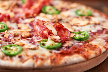 Pizza with salami, mozzarella cheese and jalapeno pepper. Wooden background. Soft focus. Copy space.	