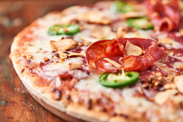 Pizza with salami, mozzarella cheese and jalapeno pepper. Wooden background. Soft focus. Copy space.	