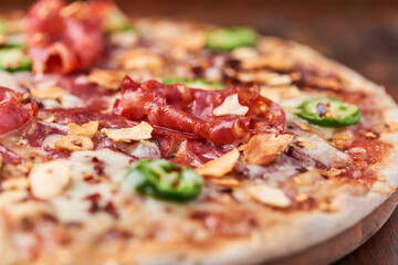 Pizza with salami, mozzarella cheese and jalapeno pepper. Wooden background. Soft focus. Copy space.	