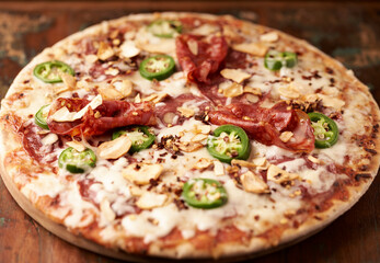 Pizza with salami, mozzarella cheese and jalapeno pepper. Wooden background. Soft focus. Copy space.	