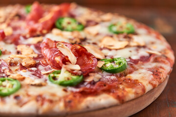 Pizza with salami, mozzarella cheese and jalapeno pepper. Wooden background. Soft focus.	