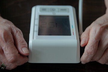 Shallow Dept of Field Photo - hands of an elderly female in her 80's with blood pressure machine between them