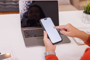 Asian woman hold smartphone use laptop at home. Project stats financial data sales charts on laptop and cellphone screen, Report preparation, synchronization for safety concept
