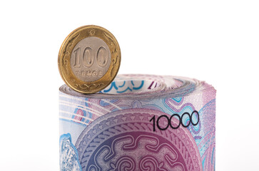 Banknotes of 10,000 Kazakhstani tenge and 100 tenge coin against the white background