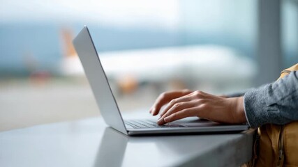 Professional businessman typing on laptop at airport lounge, showcasing digital nomad lifestyle with airplane through window, embodying remote work flexibility and global connectivity - Powered by Adobe