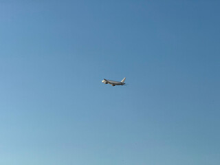 Airplane flying in clear blue sky at high altitude with visible red tailfin. Aviation, transportation, speed, and global connectivity through air travel.