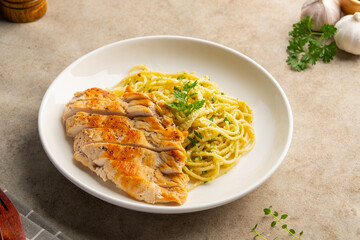 Grilled Chicken breast with spaghetti broccoli pesto sauce in a plate.