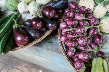 Selection of fresh eggplants, cucumbers, and other vegetables in rustic wicker basket