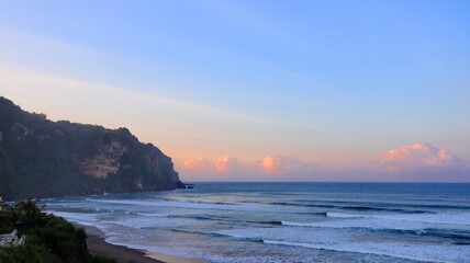 Fototapeta premium Beautiful coastal cliff with ocean waves at sunset on tropical beach, scenic seascape panorama