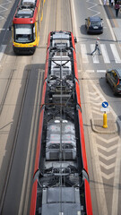 Ruchliwa ulica w mieście z jadącym tramwajem, samochodami i pieszymi. Nowoczesna infrastruktura miejska, transport publiczny i codzienny pośpiech metropolii.