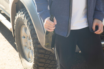 Alcohol while driving a car. A car driver with a bottle of alcohol.