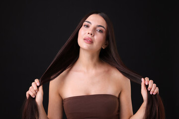 Woman with beautiful smooth hair after lamination procedure on black background