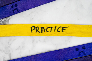 Yellow stick with handwritten word Practice placed between two purple sticks with sad face drawings...