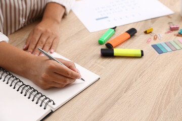 Woman using business planner at wooden table in office, closeup