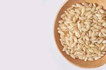 Healthy brown rice in wooden bowl on light background, healthy grains and natural nutrition concept.