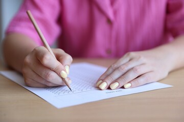 Student filling out multiple choice test at wooden table, closeup. Passing exam