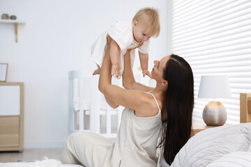 Fototapeta premium Mother and her cute little baby on bed in room