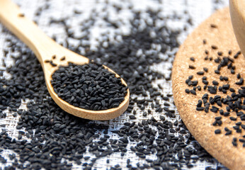 Bio natural black sesame seeds in a wooden spoon on a wooden bowl. Healthy eating, Ayurveda, spices, healthy food, alternative medicine