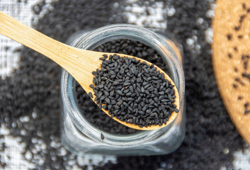 Bio natural black sesame seeds in a wooden spoon and in a wooden bowl on the table. Healthy eating, Ayurveda, spices, healthy food, alternative medicine