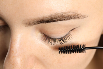 Woman applying mascara onto her eyelashes, closeup