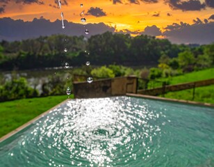 Water droplets cascade into a tranquil pool at sunset
