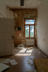 Abandoned attic interior with old wooden chairs and table under a damaged ceiling, sunlight...