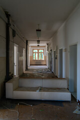 Abandoned attic interior with old wooden chairs and table under a damaged ceiling, sunlight streaming through broken windows, creating a nostalgic and eerie atmosphere of decay and emptiness.