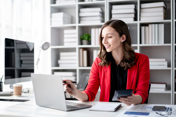 Young Adult Woman Working on Laptop with Calculator in Bright Office Analyzing Financial Data Charts Graphs for Business Growth Success and Accounting
