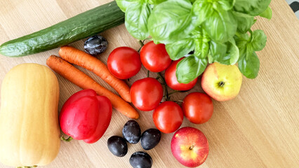 Farm-Fresh Vegetables and Fruit on Wooden Table — Top-View Vegetarian Flat Lay with Basil, Tomatoes on the Vine, Red Bell Pepper, Cucumber, Butternut Squash, Carrots, Lemon, Apples, Plums and Blueberr