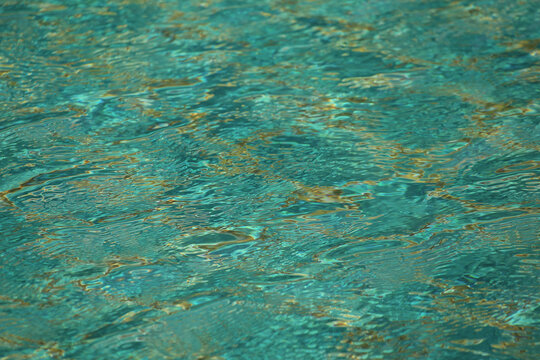 Pool with clear water is lined with blue-green tiles. Calm water is reflected in tile and creates serene atmosphere