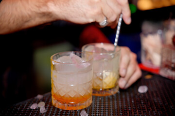 Bartender preparing alcoholic cocktails with spoon and ice in bar