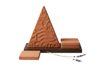 Hand-crafted earthy terracotta tiles, varied textures, delicate dried lavender, on dark wooden plinth, transparent studio background, minimalist design refined craftsmanship