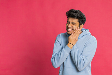 Dental problems. Indian Hindu man touching cheek, closing eyes with expression of terrible suffer...