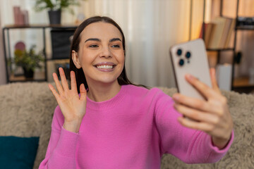 Young woman at home having video call smiling, laughing and actively gesturing while talking to a...