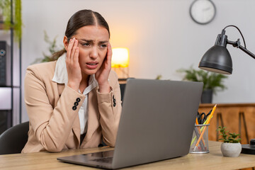 Young businesswoman at home office rubs temples feels strong headache and pauses work on laptop. Freelancer girl at table drinks water takes pill sets short timer closes eyes and rests then resumes