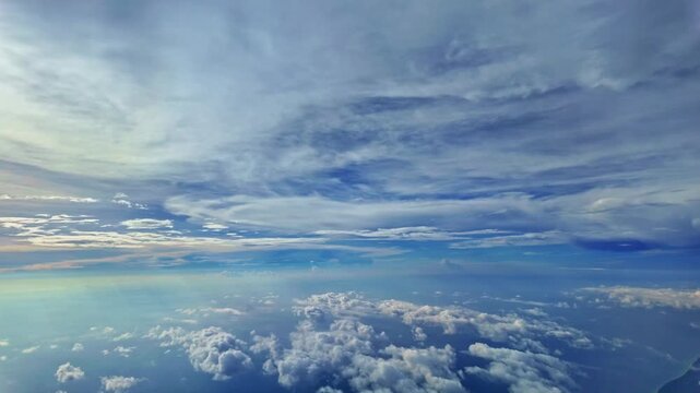 
White fluffy clouds float in the air.
by the airplane window.
Light shines through the beautiful sky at sunset and large clouds cover the city.
The slope of the horizon shifts with the airplane.