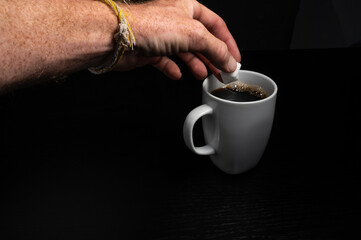 Hand Adding Sugar Cube to Coffee Mug