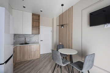 modern kitchen/dining area with sleek cabinets, a round table with gray chairs, and minimalist decor. The lighting is soft