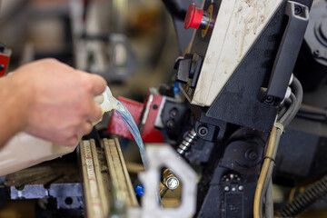 Adding coolant to a large hacksaw for metal and wood. Industrial machine maintenance
